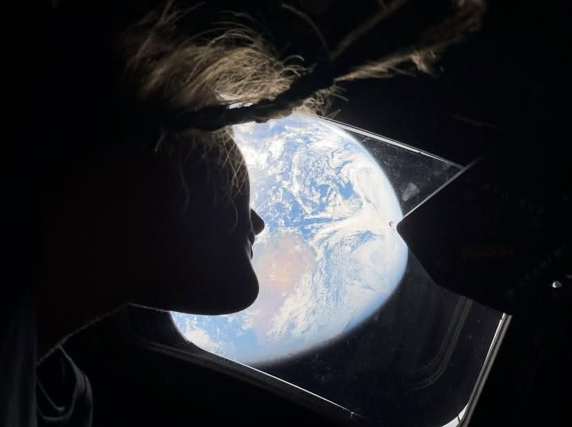 Astronaut viewing Earth from orbit through a spacecraft window